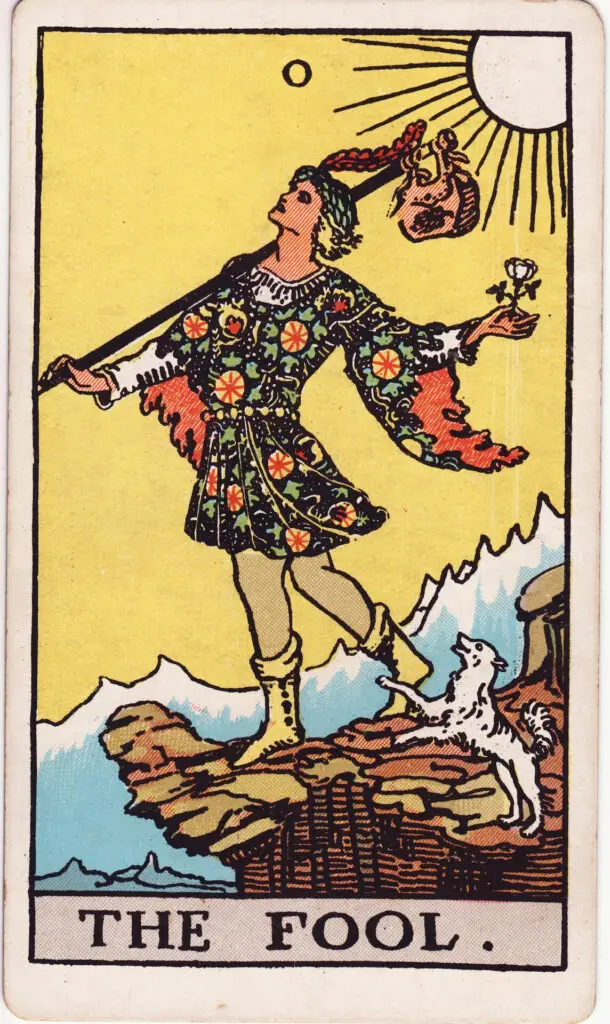 Carte du tarot Rider-Waite représentant Le Fou (Le Mat), un jeune homme au bord d’une falaise, avec un baluchon, un chien blanc et un ciel lumineux. Illustration de 1909 par Pamela Colman Smith.