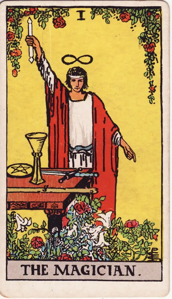 Carte du Magicien dans le tarot Rider-Waite : un homme debout devant une table, tenant un bâton levé vers le ciel, entouré des quatre symboles du tarot. Illustration de 1909 par Pamela Colman Smith.