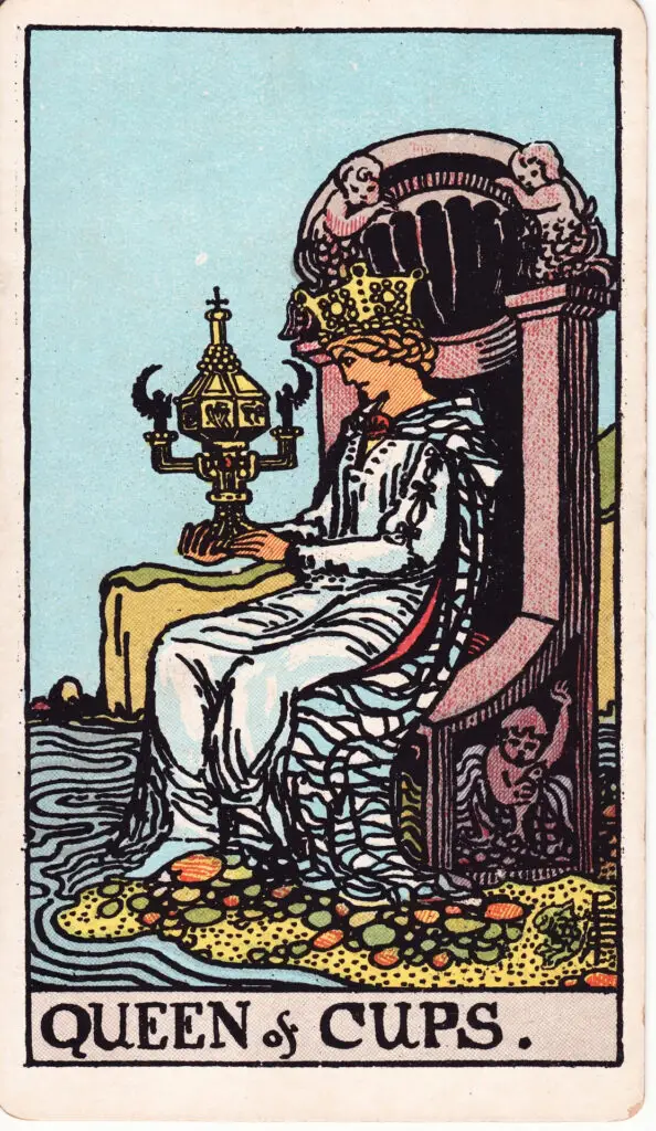 Illustration de la Reine de Coupes du tarot Rider Waite : une reine est assise sur un trône en bord de mer, contemplant une coupe décorée fermée, symbole d’intériorité et de profondeur émotionnelle.