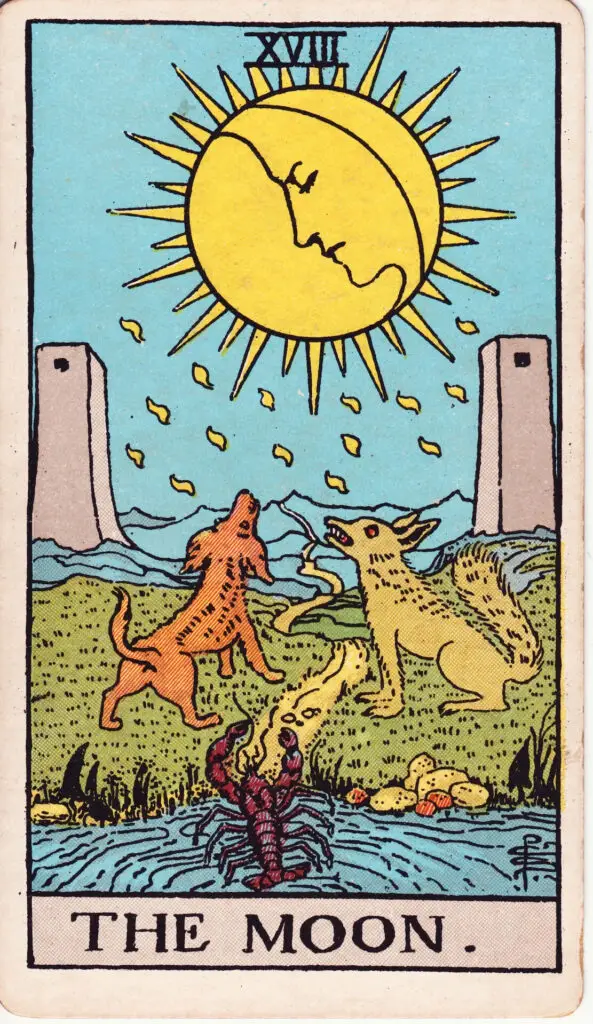 Carte de La Lune dans le tarot Rider-Waite : une lune aux traits humains éclaire un paysage nocturne avec deux tours, un chien, un loup et un crustacé sortant de l’eau. Illustration de 1909 par Pamela Colman Smith.