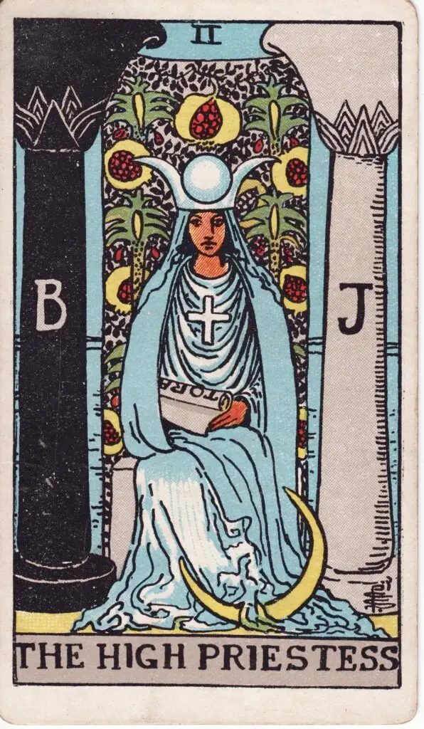 Carte de la Grande Prêtresse dans le tarot Rider-Waite : une femme assise entre deux colonnes, tenant un rouleau, voilée, couronnée, entourée de symboles spirituels. Illustration de 1909 par Pamela Colman Smith.