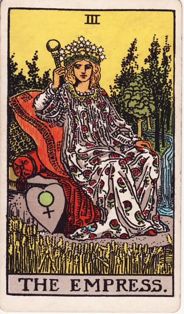 Carte de l’Impératrice dans le tarot Rider-Waite : une femme couronnée, assise sur un trône au cœur de la nature, entourée de symboles de fertilité. Illustration de 1909 par Pamela Colman Smith.