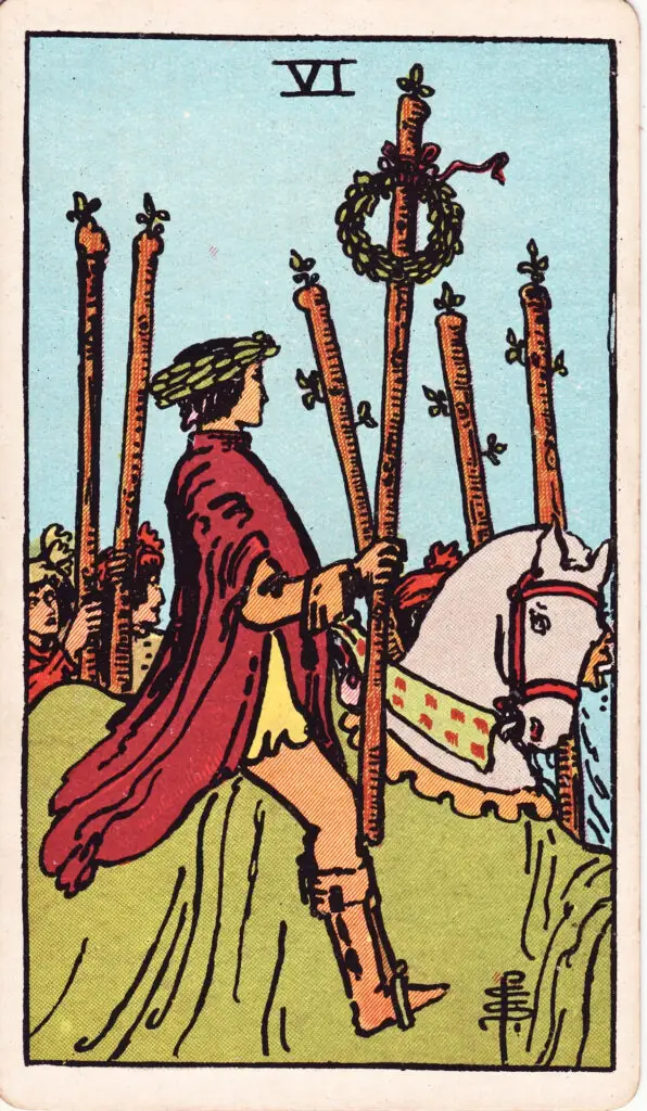 Illustration du Six de Bâtons du tarot Rider-Waite : un cavalier victorieux avance sur un cheval blanc, une couronne de laurier sur la tête, salué par la foule et tenant un bâton orné de lauriers.