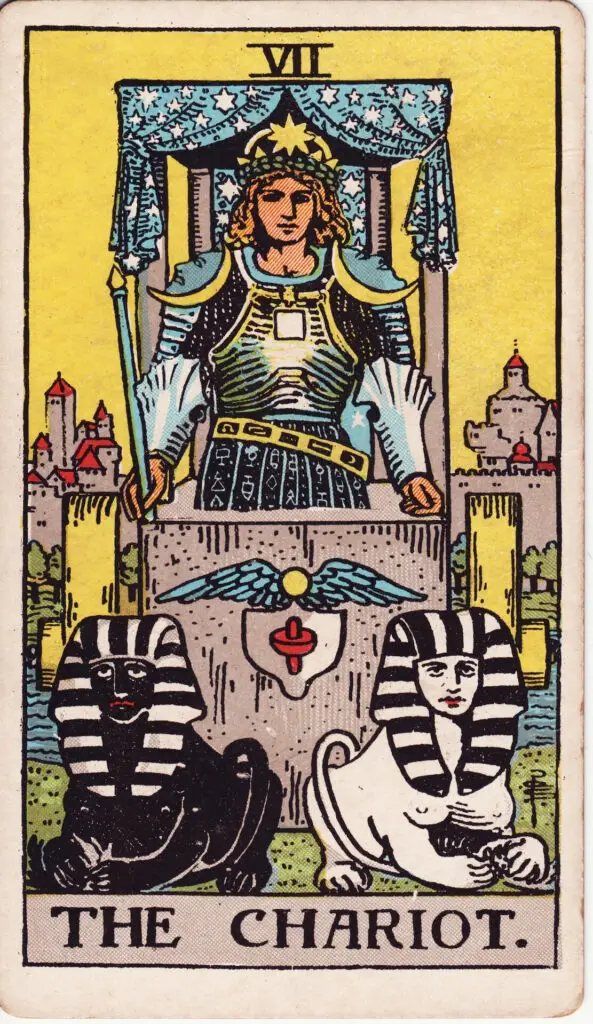Carte du Chariot dans le tarot Rider-Waite : un homme en armure conduit un char tiré par un sphinx noir et un sphinx blanc, sous un ciel étoilé. Illustration de 1909 par Pamela Colman Smith.