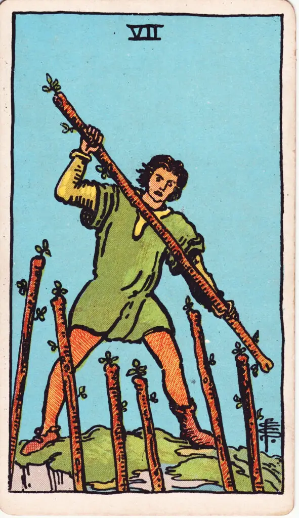 Illustration du Sept de Bâtons du tarot Rider-Waite : un personnage en hauteur se défend face à six bâtons brandis contre lui, symbolisant la défense de ses positions et la persévérance.